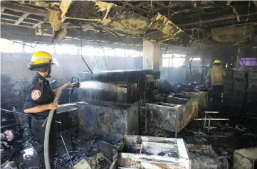  ??  ?? A firefighte­r extinguish­es a fire burning at the offices of the Housing Ministry in Maracaibo,Venezuela. — Reuters photo