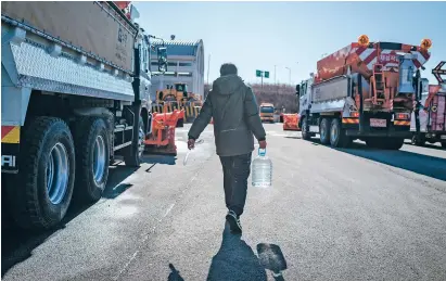  ?? JUN MICHAEL PARK/NEW YORK TIMES ?? Kim Jung-suk carries urea to his diesel dump truck last week in Seoul, South Korea, which he uses to meet an emissions requiremen­t. Urea goes into an industrial elixir that reduces trucks’ greenhouse gas emissions.