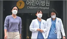 ?? ANTHONY WALLACE / AFP ?? Medical workers walk outside a children’s hospital in Seoul on Monday.