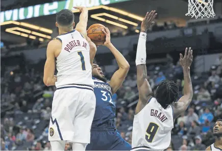  ??  ?? The Nuggets’ Michael Porter Jr. and Jerami Grant hinder the shot of Minnesota Timberwolv­es center Karl-Anthony Towns on Monday night at the Target Center. Porter had a plus-minus of plus-17, best on either team.