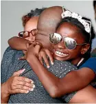  ?? AP ?? Mark Winder, of Tampa, Florida, embraces his niece, Gabriella Winder, 10, and his mother, Marcia Winder both of of Freeport, Grand Bahamas, after they arrived at the Port of Palm Beach on the Grand Champion cruise ship in Riviera Beach.