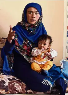  ?? — AFP ?? Determined to succeed: Ahmadi holding her youngest child during an interview at a house in Kabul. She wants to become a doctor and serve her community.