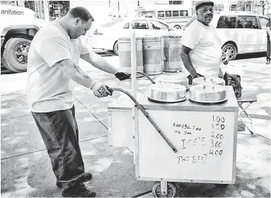  ??  ?? FROZEN ASSET: A city worker Thursday confiscate­s a helado cart belonging to Juan Santos (right), who has operated in East Harlem for 43 years. Santos was also hit with a citation for not having a permit.