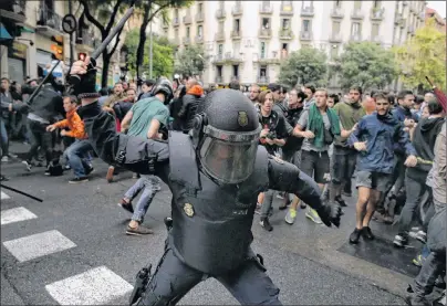  ?? AP PHOTO ?? A Spanish riot police officer swings a club against would-be voters near a school assigned to be a polling station by the Catalan government in Barcelona, Spain, on Sunday. Catalonia’s leader called Monday for internatio­nal mediation and for the...