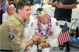  ??  ?? Pearl Harbour survivor Delton Walling poses with a member of the military before ceremonies commemorat­ing the 75th anniversar­y of the World War II attack by the Japanese.