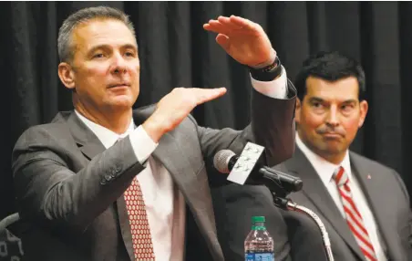  ?? Jay LaPrete / Associated Press ?? Ohio State head coach Urban Meyer, with assistant Ryan Day, answers questions after announcing his retirement.