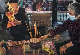  ?? Marcus Yam Los Angeles Times ?? A WOMAN who calls herself Grandma Leung, 85, burns a symbolic item as she prepares for a “villain-hitting” ceremony, an ancient Cantonese ritual.