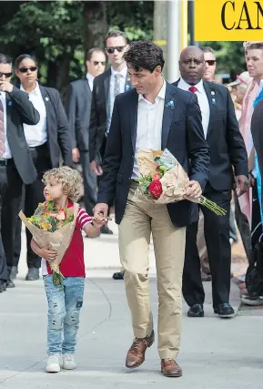  ?? ANDREW VAUGHAN/THE CANADIAN PRESS ?? Prime Minister Justin Trudeau and his son Hadrien, 4, place flowers outside the police station in Fredericto­n on Sunday in memory of two officers killed Friday.