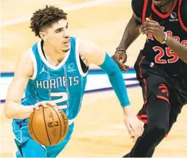  ?? JACOB KUPFERMAN AP ?? Hornets guard Lamelo Ball, who had 23 points and nine rebounds, drives to the basket while being guarded by Raptors forward Chris Boucher.