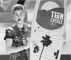  ?? PHOTOS: KEVIN WINTER, GETTY IMAGES ?? Canadian pop star Justin Bieber accepts the Male Summer Music Star award at the 2012 Teen Choice Awards on Sunday.