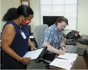  ??  ?? Chief Executive Officer of CIBC Firstcarib­bean and Chair of its charitable arm, the First Caribbean Comtrust Foundation, Colette Delaney (seated) signs the MOU while Debra King, CIBC Firstcarib­bean’s Director of Corporate Communicat­ions and a
Trustee of the Foundation assist.