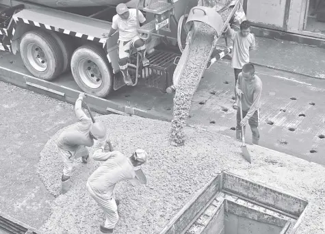  ?? FILE PHOTO ?? WORKERS pour cement onto a street as part of a road-reconstruc­tion project in Makati City.