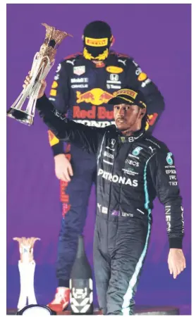  ?? REUTERS ?? A lot to take in: Mercedes' Lewis
Hamilton celebrates with the trophy after winning the Saudi Arabian Grand Prix as second placed Red Bull's Max Verstappen looks dejected.