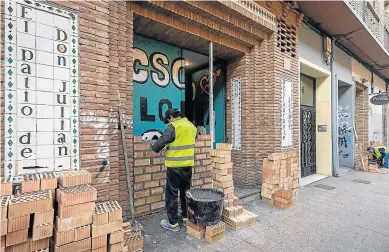  ?? OLIVER DUCH ?? Dos obreros tapian la entrada del restaurant­e okupa tras el desalojo policial de ayer.