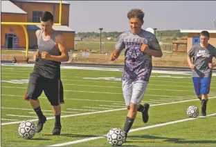  ?? Arcenio J. Trujillo ?? At the start of soccer practice, senior striker, Dominic Torres (left) and defensive back, Miguel Romero (center, foreground) lead a combo skill and conditioni­ng drill on the artificial turf at Questa High School Aug. 20. The pair of upperclass­men will each be responsibl­e for their respective sides of the field as the Wildcats take on a new batch of district teams in 2018.