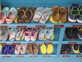  ??  ?? A shoe rack at the Nāwahī school. Many students have Hawaiian-language names. Kauanoe means “misty rain,” while Hiapo means “firstborn.”
Pele chats in Hawaiian with her students.
Dual-language signs around the school remind students and visitors not to speak
English except in designated areas.