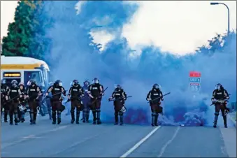  ?? aP-John Minchillo ?? Police in riot gear prepare to advance on protesters Saturday in Minneapoli­s. Protests continued following the death of George Floyd, who died after being restrained by Minneapoli­s police officers on Memorial Day.