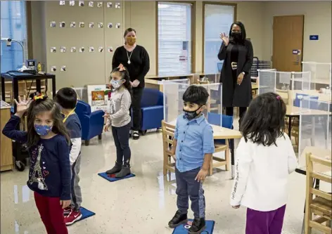  ?? ASHLEE REZIN garcia / Chicago SUN-TIMES via ap ?? Chicago Public Schools CEO Janice Jackson, background right, waves to students in a preschool classroom at dawes Elementary School in Chicago in January. U.S. guidelines that say students should be kept 6 feet apart in schools are receiving new scrutiny from federal health experts, state government­s and education officials working to return as many children as possible to the classroom.