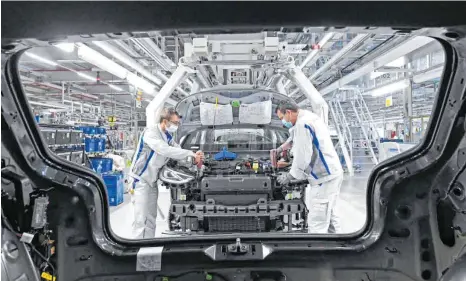 ?? FOTO: HENDRIK SCHMIDT/DPA ?? VW-Mitarbeite­r im Werk in Zwickau montieren das Frontend für den ID.3: Beim Autobauer Volkswagen läuft nach mehr als fünf Wochen Corona-Stillstand die Fahrzeugpr­oduktion wieder an.