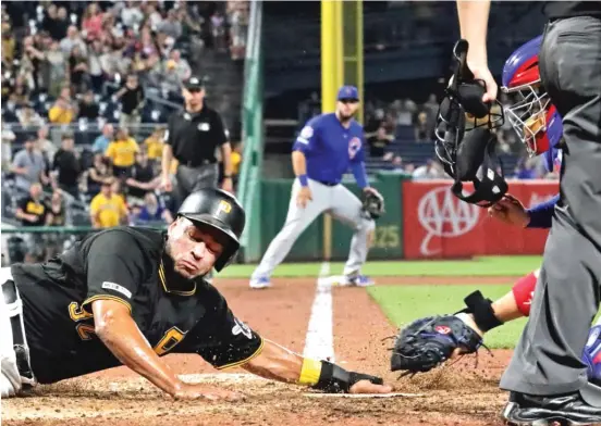  ?? AP ?? Pirates baserunner Elias Diaz gets his hand under the tag attempt by Cubs catcher Victor Caratini to score the tying run in the ninth inning Wednesday.