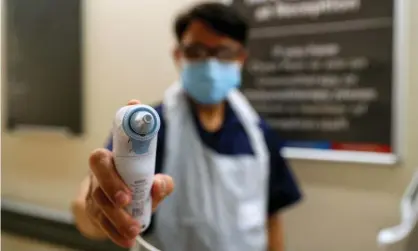  ??  ?? A nurse in PPE holds a thermomete­r at Wexham park hospital in Berkshire. Photograph: Steve Parsons/AFP/Getty Images