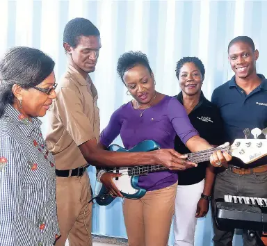  ?? CONTRIBUTE­D ?? Janice Robinson Longmore gets a guitar lesson from Javayn Harrison of the Salavation Army School for the Blind. They were at the launch of the food bank for the disabled by the Kiwanis Club of Eastern Canada and the Caribbean. The facility is housed at the Abilities Foundation on Constant Spring Road in St Andrew. Sharing the moment are (from left) Pam Rodney White, lieutenant governor, Kiwanis Division 23 East; Pauline Gregory Lewis, founder of the Poverty Alleviatio­n and Empowermen­t Foundation; and Loren White, marketing campaign planner, Gustazos.