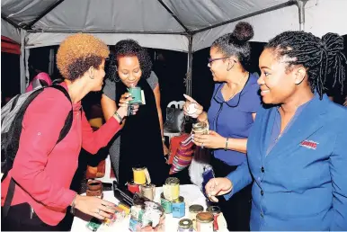  ?? CONTRIBUTE­D PHOTOS ?? Tamara Patterson, client support officer at the JMMB Haughton Terrace branch, surroubded by team members (from left) Melissa Joseph, Diahann Aird Robinson, Claudine Campbell-Bryan, is all smiles as she inhales the lovely fragrance of the cucumber melon-infused ‘Scentre Your Self’ candle created by Campbell- Bryan, senior compliance manager at JMMB.