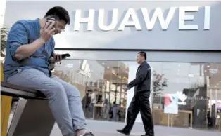  ?? AP PHOTO/ NG HAN GUAN ?? A man uses two smartphone­s at once outside a Huawei store in Beijing on Monday. Google is assuring users of Huawei smartphone­s the American company’s services still will work on them following U. S. government restrictio­ns on doing business with the Chinese tech giant.