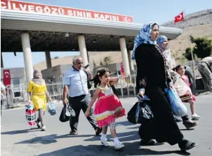  ?? BULENT KILIC/AFP/GETTY IMAGES FILES ?? Refugees entering Turkey in August through the Cilvegozu crossing gate at Reyhanli, are among thousands fleeing Syria. Those who can afford it are being smuggled in comfort into Europe.