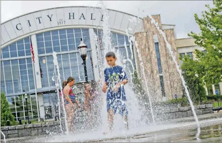  ?? JONATHAN PHILLIPS / SPECIAL ?? Dante Miller (center) runs through the fountain at Town Center Park in Suwanee.