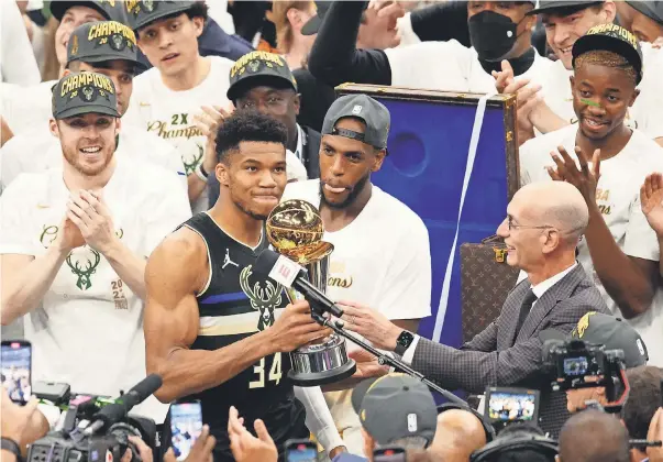  ?? MARK J. REBILAS/ USA TODAY SPORTS Game 6 ?? Giannis Antetokoun­mpo accepts the Bill Russell NBA Finals MVP Award from Commission­er Adam Silver after he scored 50 points in the Bucks’ series- clinching victory against the Suns on Tuesday.