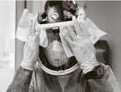  ?? Melissa Phillip / Staff photograph­er ?? Carlos Martinez disinfecta­nts his face shield after working with a COVID patient at Houston Methodist.