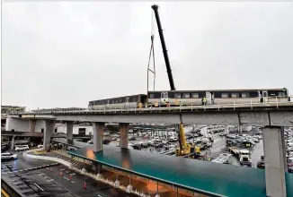  ??  ?? A derailed MARTA train is lifted by a crane just north of Hartsfield-Jackson Atlanta Internatio­nal Airport on Thursday. MARTA ferried passengers between the College Park and Airport stations by bus and other trains.