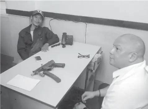  ?? MITZI AMBRAD ?? Former rebel Manuel Roble Valejo (left) of Danao City surrendere­d his KG-9 machine pistol to Capitol Civil Security Unit head Bobby Legaspi. (story on page 9)