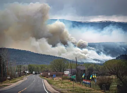  ?? JIM WEBER/NEW MEXICAN FILE PHOTO ?? The Hermits Peak/Calf Canyon Fire burning near Cleveland, N.M., darkens the sky over Mora in 2022. Residents in the Mora area met with federal and state officials at a town hall this week to express their frustratio­ns about how their fire damage claims have been handled.