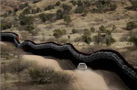  ?? AP FILE PHOTO/CHARLIE RIEDEL ?? This 2019 file photo, shows a Customs and Border Control agent patrolling on the US side of a razor-wirecovere­d border wall along the Mexico east of Nogales, Ariz.