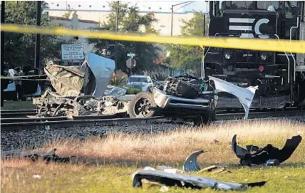  ?? JOE CAVARETTA/SOUTH FLORIDA SUN SENTINEL PHOTOS ?? A driver was killed when his vehicle collided with a Brightline train at Dixie Highway and NW 6th Street in Pompano Beach Monday. An oncoming freight train was stopped ahead of the strewn wreckage early Monday.