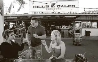  ?? Kin Man Hui / Staff photograph­er ?? Chloe Bonilla, from left, Matt Palacios and Laura Floyd enjoy drinks at Hills & Dales Icehouse on the Northwest Side. Its owner plans to leave mask-wearing up to his patrons — but also his staff.