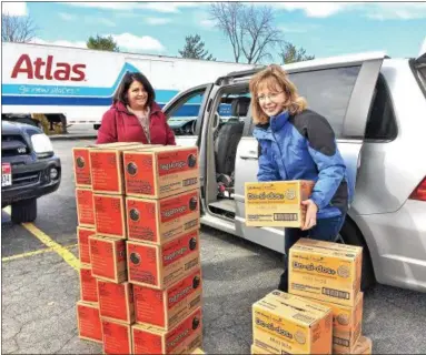  ?? PHOTOS BY GLENN GRIFFITH — GGRIFFITH@DIGITALFIR­STMEDIA.COM ?? Amy Williams, left, and Michele Kuhns, right, make sure they have the correct number of Girl Scout cookies for Troop 2429 after making a cookie pickup Friday in Clifton Park.