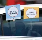  ?? Associated Press ?? ■ Two young children hold signs through the car window that make reference to the 2020 U.S. Census on June 25 as they wait in the car with their family at an outreach event in Dallas.