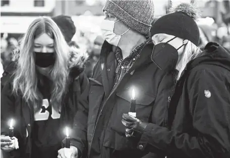  ?? Helen H. Richardson, The Denver Post ?? Amy and Jim Getzoff take part in a candleligh­t vigil Wednesday with daughter Brooke, 14, left, to honor the victims of the shooting at King Soopers. Hundreds turned out for the event in front of the Boulder County Courthouse on the Pearl Street Mall.