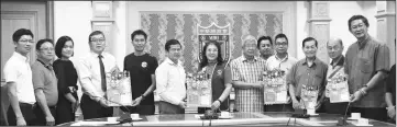  ??  ?? Lee (sixth left) hands over the poster to Lions Club Internatio­nal 308-A2 past district governor Mary Law. The Lions Club will partner with the chamber to promote the charity run.