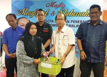  ??  ?? Almain presenting aid to a recipient during the program in Keningau yesterday.