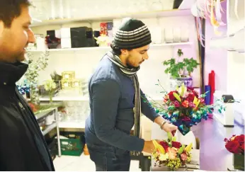 ?? (AP FOTO) ?? IN CASE YOU FORGET. In this Nov. 30, 2016 photo, Youssef Hassan (right) prepares a bouquet for Michael Levine at After Hours Flowers in New York. The company’s recent calls have come from Saudi Arabia, Colombia, Switzerlan­d, Mexico and the Philippine­s.