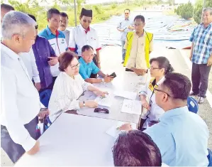  ??  ?? CHRISTINA berbincang berkenaan mempercepa­tkan usaha baik pulih jalan rosak di laluan menuju lapangan terbang.