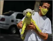  ?? (AFP via Getty Images/TNS/Federico Parra) ?? A man wears a face mask while he carries his dog with a protective suit as a preventive measure against the spread of the new coronaviru­s, covid-19, in Caracas, Venezuela, on March 20. People are worried about their pets, and doctors are advising precaution­s.