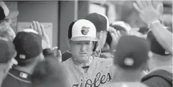  ?? KARL MERTON FERRON/BALTIMORE SUN ?? Mark Trumbo makes his way through teammates’ high-fives and a shower of sunflower seeds after hitting his 30th home run of the season, a two-run shot in the first inning. He also homered in Friday’s first inning.