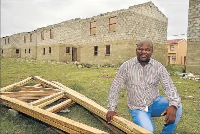  ?? Pictures: EUGENE COETZEE ?? TRUSSED UP: The metro’s political head of human settlement­s, Nqaba Bhanga, with some roof trusses recovered after houses in the area were looted on Monday. Behind him are the controvers­ial incomplete RDP homes in NU 29 Motherwell