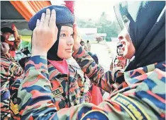  ??  ?? Cadet Zahirah Md Ariffin adjusts fellow cadet Nur Atikah Amran’s beret while preparing for the official ceremony. A total of 704 cadets from across the country are taking part in the five-day camp. — Bernama photo