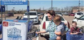  ?? COMMERCIAL APPEAL ?? Ashley Toth carries her son Breylon while her other son, Greyson, is pushed in a cart after purchasing a kitchen toy from Toys R Us on Winchester. BRAD VEST/THE